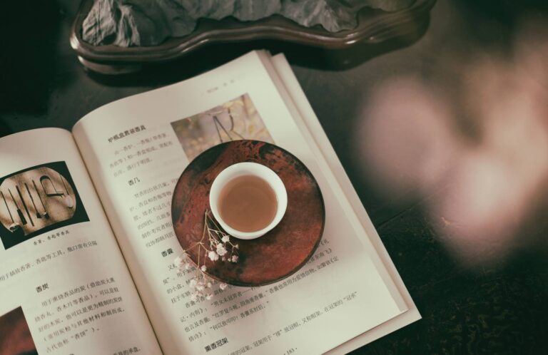 Livro na língua chinesa, aberto, com um chá em cima.